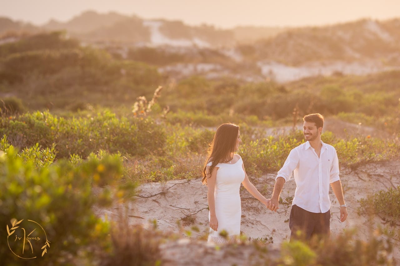 Casal caminhando de mãos dadas na praia em Florianópolis.